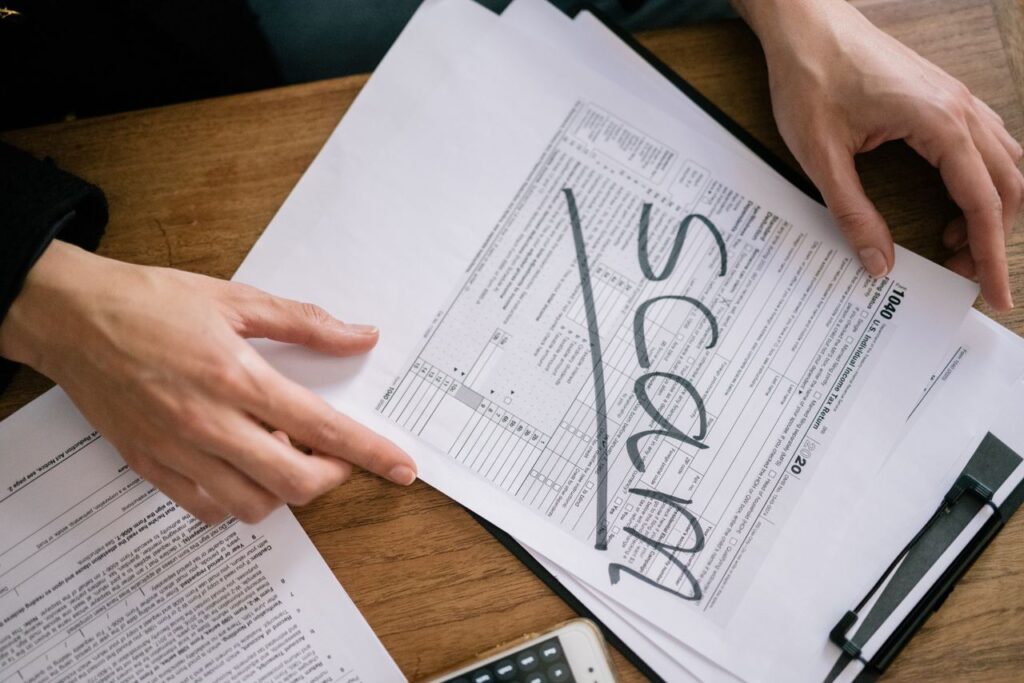 Documents highlighting tax fraud with the word 'scam' on tax forms.